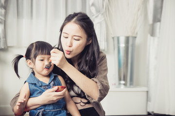 Little Asian girl eating fruit from mother feeding.