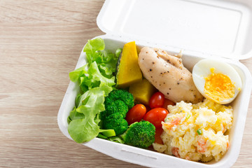 Healthy salad with tomatoes, chicken, egg, mash potato, and mixed greens (Broccoli, pumpkin) on wooden background. Healthy food.