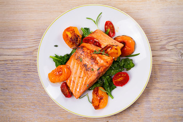 Salmon fillet with spinach, tomatoes and herbs. View from above, top studio shot, horizontal