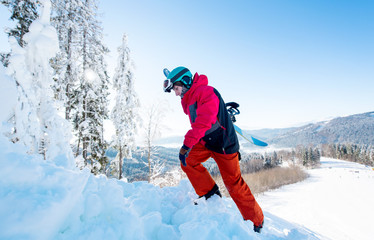 Fototapeta na wymiar Full length shot of a freerider snowboarder carrying his snowboard, climbing up to the mountain copyspace active sports lifestyle recreation winter seasonal people