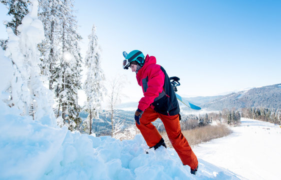 Full length shot of a freerider snowboarder carrying his snowboard, climbing up to the mountain copyspace active sports lifestyle recreation winter seasonal people