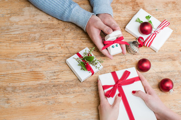 Romantic couple exchanges holiday Christmas gifts on a wooden table with Christmas decorations with room for copy