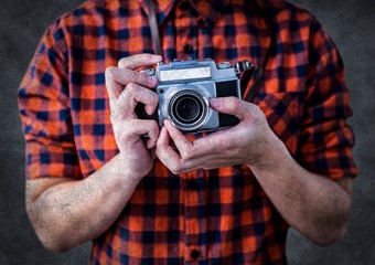 Millennial man mid section with camera against grey background