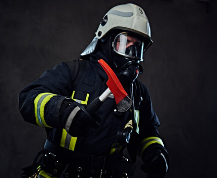 Firefighter dressed in a uniform holds a red axe.