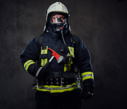 Firefighter dressed in a uniform holds a red axe.
