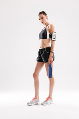 Full length portrait of an exhausted young sportswoman in earphones