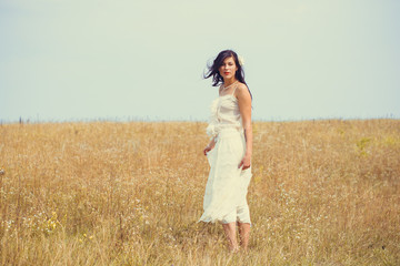 Young beautiful simple rural bride in lacy dress at romantic style , stands in the meadow. Portrait tenderness and happy woman, vintage texture