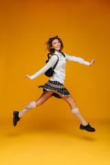 Fototapeta na wymiar Full length portrait of a smiling cheerful schoolgirl in uniform
