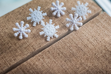Beautiful white plastic snowflakes close-up on a wooden background.