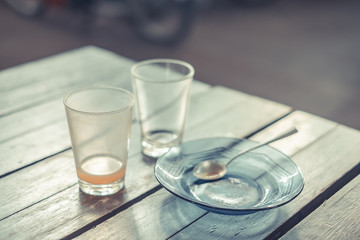 Empty glass of hot tea in with saucer and spoon on wooden table vintage tone, shallow focus.