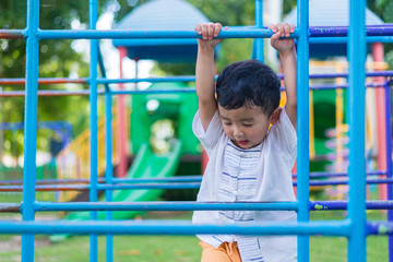 Obraz premium Asian boy hang the metal bar at outdoor playground.