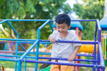 Obraz premium Asian boy hang the metal bar at outdoor playground.
