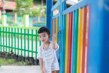 Sad Asian kid behind the grid trying to escape. shallow DOF