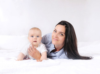 Mom and baby boy playing in sunny bedroom