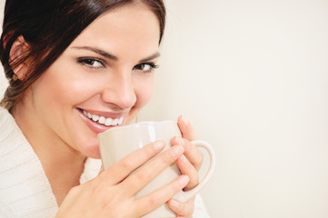 Young woman with long hair and brown eyes drinking coffee or tea from a cup