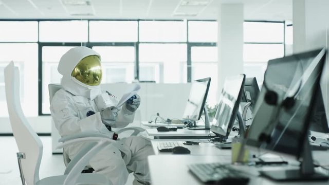  Astronaut sitting at desk in room full of computers using touch screen