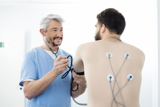 Doctor Examining Patient With Electrodes Attached On Back