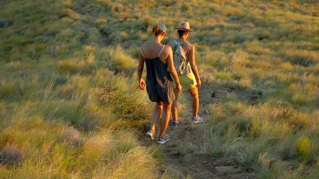Women walking down from the mountain, slow motion shot at 240fps, steadycam shot   
