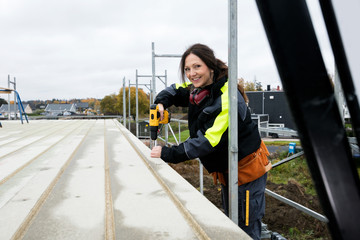 Fototapeta na wymiar Female Carpenter Drilling Roof At Construction Site