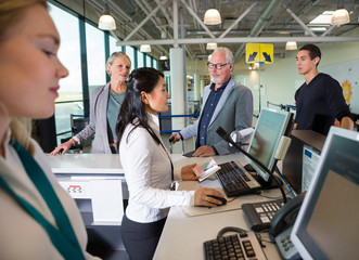 Naklejka premium Staff Checking Passport On Computer While Passengers Waiting In 