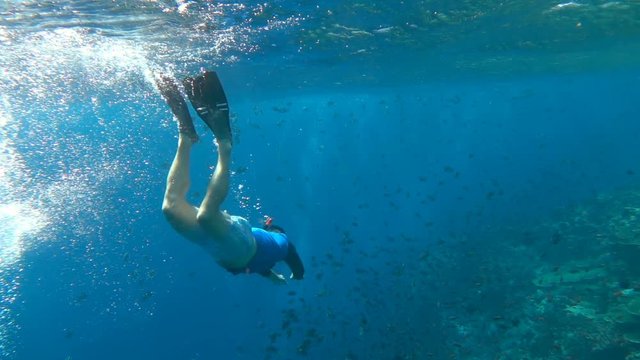 Man wearing flippers and swimming under the water, slow motion shot at 240fps, steadycam shot
