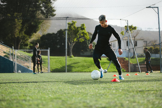 Football player practice dribbling on field
