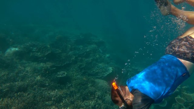 Man swimming with his son under the water, slow motion shot at 240fps, steadycam shot 
