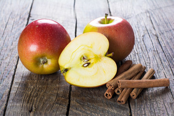 Apples with cinnamon on wooden surface