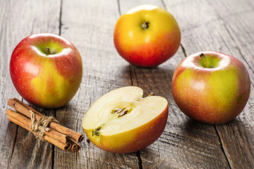 Apples with cinnamon on wooden surface