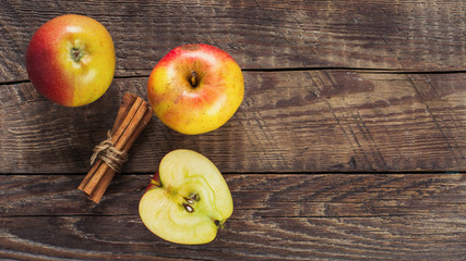 Apples with cinnamon on wooden surface