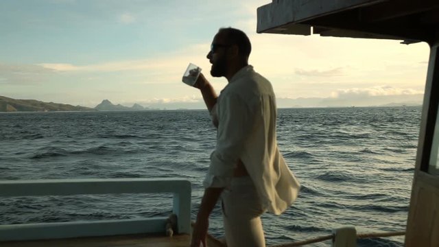 Man drinking coffee on the luxury yacht, slow motion shot at 240fps, steadycam shot
