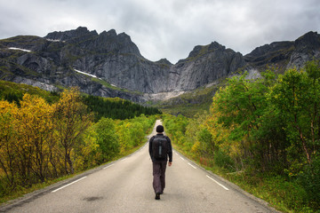 Hiker walks on a scenic road on Lofoten islands in Norway