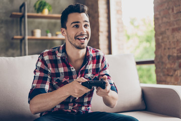 Close up of attractive hipster with bristle and toothy grin, holding joy stick and playing...