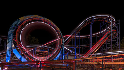  Attraction in the park. Roller coaster in motion at night. A long exposure photo