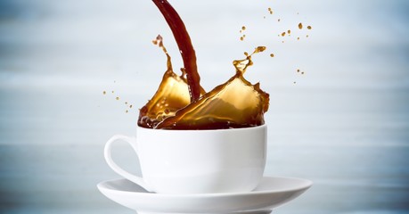 Coffee being poured into white cup against blurry blue wood