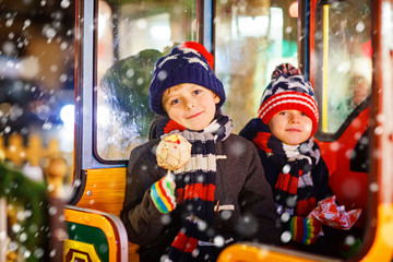Two little kids boys on carousel at Christmas market