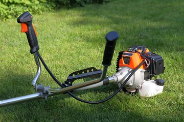 Brush cutter handles in the grass detail