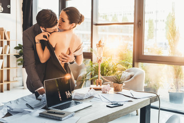 Young couple making out in office - obrazy, fototapety, plakaty