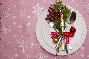 Christmas table place setting with pine branches,ribbon and bow.