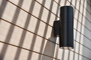 Cylinder Black wall lamp on wooden wall.