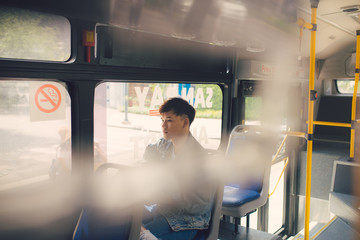 Young  asian man on commute travel to work sitting in bus or train.