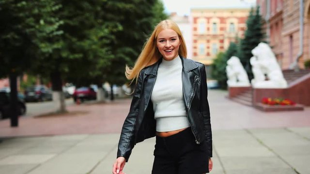 Young woman walking in the street on camera and turn around with playful smile on joyful mood