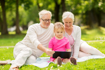 grandparents and granddaughter with tablet pc