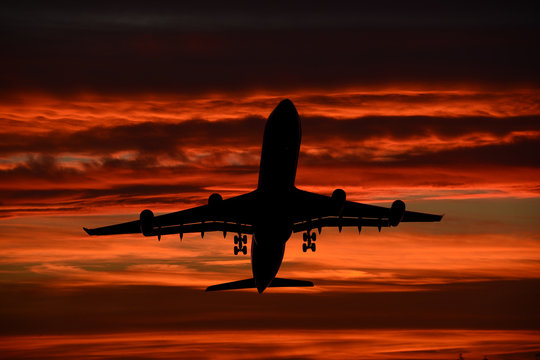 passenger airplane taking off  with orange sunset clouds composition photography