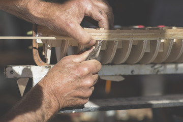 handcrafted craftwork of a wooden boat model / old man working on creating a wooden model of a boat...