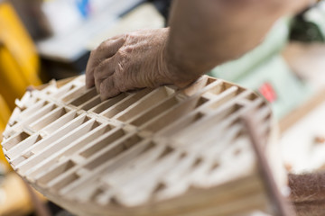 handcrafted craftwork of a wooden boat model / old man working on creating a wooden model of a boat...