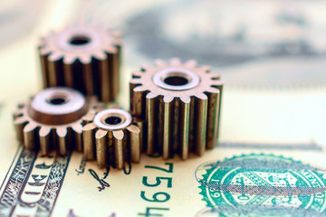 metal gears on dollar banknotes