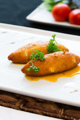 Chop chicken fillet stuffed with juicy butter, cheese and greens on a white rectangular plate, chicken rolls, chicken Kiev served with butter sauce and decorated with fresh parsley stems on place mat
