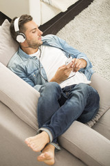 Fototapeta premium Cheerful man relaxing in sofa, listening to music