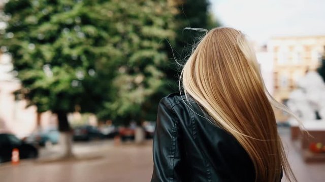Beautiful girl in walking on the street turning around and looking at the camera.